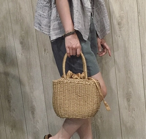 Detail of hand-woven straw tote with thick drawstring inner lining and curved handle