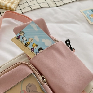 Pink and beige canvas crossbody bag with cartoon flap detail and clear front pocket