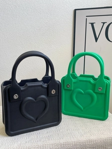 Detail of square EVA beach bags in black and green with embossed heart patterns