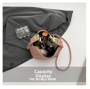 Pink suede crossbody bag with gold hardware showing interior storage for phone and lipstick