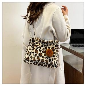 Leopard print faux fur shoulder bag with chain strap and plush ball detail in use