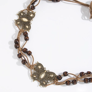 Detail of bohemian braided belt with wooden beads and rhinestone butterfly metal buckles