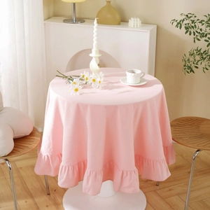 Detail of pink cotton tablecloth with ruffled edges on a round table in cozy room decor