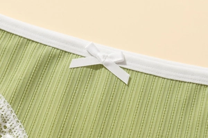 Close-up of light green ribbed panties with white lace trim and a delicate bow detail