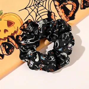 Detailed view of Halloween silk scrunchie with skull and music notes pattern on orange background
