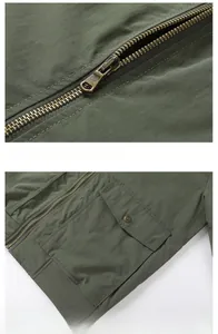 Detail view of olive green flight jacket featuring smooth bronze zipper and snap pocket