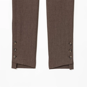 Détail de l'ourlet de pantalon marron foncé avec boutons latéraux et fente discrète
