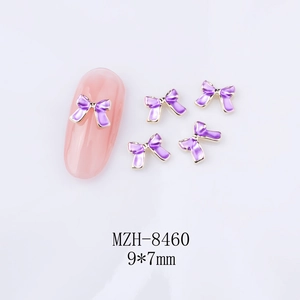 Détail d'un bijou d'ongle en émail violet de 9x7mm en forme de nœud sur un faux ongle