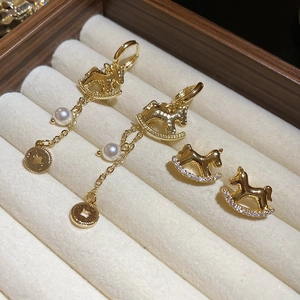 Détail de boucles d'oreilles cheval à bascule avec perles et pièces sur velours