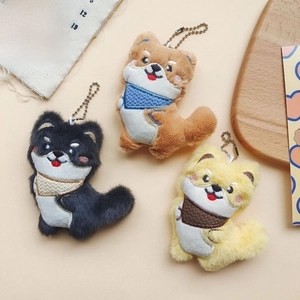 Close-up of cute Shiba Inu plush keychains in black, brown and yellow with knit scarves