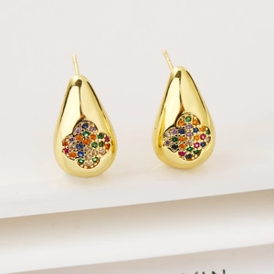 Macro detail of gold-plated drop earrings with a colorful zircon clover flower inlay