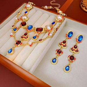 Detail of vintage gold-layered necklace and earrings with red blue stones and pearls