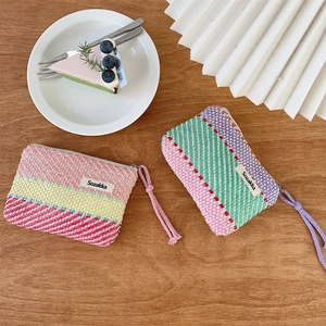 Close-up of colorful striped woven makeup bags with zipper and branded Sozakka tag