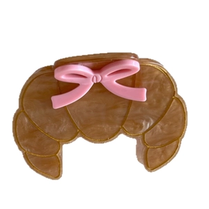 Creative croissant hair claw clip with pink bow design on a white background