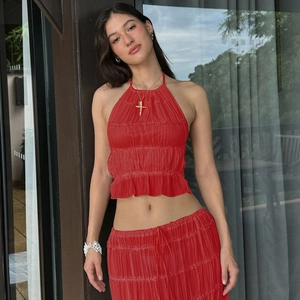 Dettaglio di top corto allacciato al collo in chiffon rosso e gonna lunga coordinata