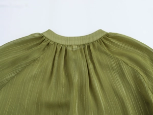 Close-up of olive green chiffon fabric with pleated texture and metallic thread details