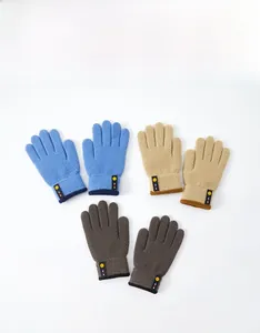 Three pairs of knit gloves for kids in blue, beige, and grey with cute smiley face patches