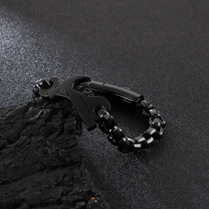Detail of matte black stainless steel hammer tool bracelet on a textured rock surface