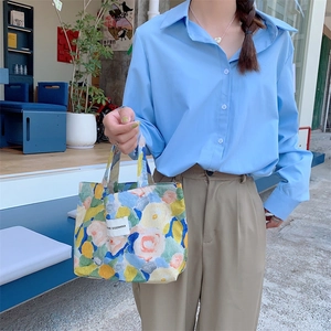 Vue détaillée d'un sac à main vintage en toile avec motifs floraux colorés et étiquette