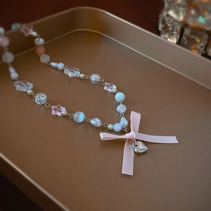 Sweet opal beaded necklace with pink bow and silver heart pendant on gold tray