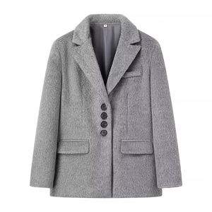 Detailopname van de grijze imitatiebonttextuur en vier zwarte ronde knopen op de lange blazer
