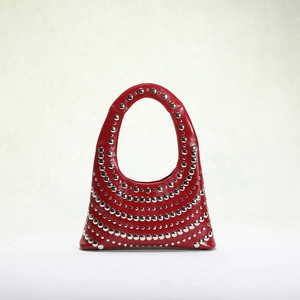 Detailed close-up of glossy red leather shoulder bag with silver rivet stud accents