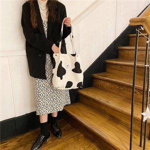 Detalle de un bolso shopper de pana con estampado de vaca en blanco y negro y asa tejida