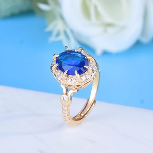 Detailed macro view of an oval sapphire blue gemstone ring with a gold halo setting