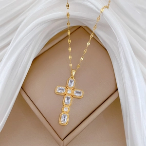 Détail du collier croix en acier titane doré avec zircons sur boîte à bijoux beige