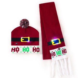 Detail of red knitted Christmas hat and scarf set with glowing LED lights and HO HO HO text