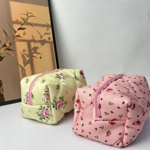 Detail view of floral quilted cotton makeup bags with pink zippers and diamond texture