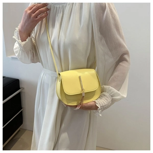 Detail of yellow semi-circular crossbody bag featuring sleek metal tassel and strap