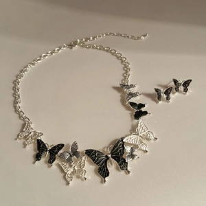 Detailed view of silver butterfly necklace and stud earrings set with black enamel inlay