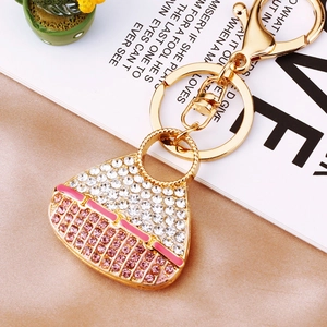 Detail of a handbag-shaped keychain with white and pink rhinestones on silk fabric