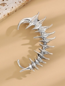 Detail of silver dragon bone ear cuff with punk gothic spine design and metallic texture