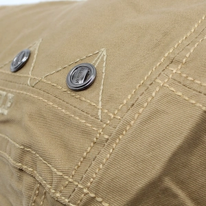 Close-up of khaki cotton beret showing heavy canvas texture and engraved metal button