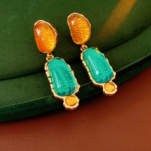 Macro view of vintage style gold-rimmed resin earrings with amber and turquoise green stones