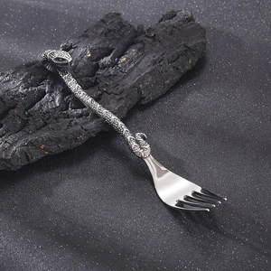 Gothic snake handle stainless steel dinner fork on black volcanic stone background