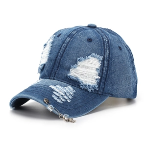 Close-up of distressed denim baseball cap featuring torn details and a silver cross pendant