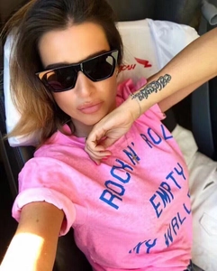 Dettaglio degli occhiali da sole cat-eye neri con una maglietta rosa alla moda