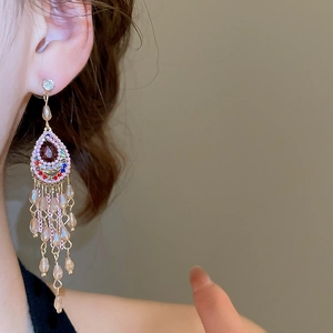 Detailed close-up of water drop crystal earrings with pink beaded tassels on model