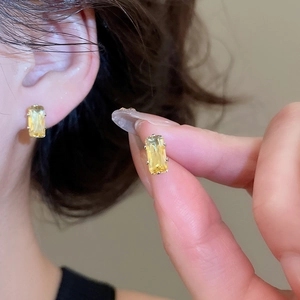 Detail of a rectangular yellow zircon earring in a classic four-prong gold setting
