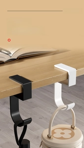 Detail view of the black and white metal hooks clamped on desk edge for bags
