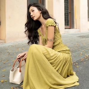 Détail de robe à col en V jaune moutarde avec poignets à volants et lien à la taille