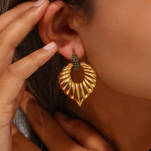 Detail of 18K gold-plated leaf earring with green zircon pavé on model's ear