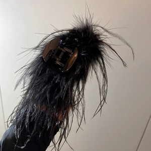 Close-up of elegant black ostrich feather hair claw clip with metallic spring detail