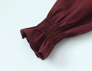 Détail de chemise bordeaux montrant des poignets élastiques froncés et tissu alvéolé