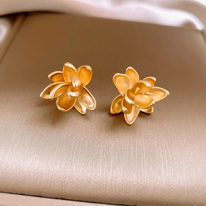 Macro shot of gold leaf earrings featuring a matte metallic layered flower design