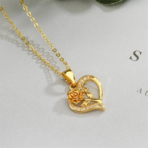 Macro shot of gold heart pendant with rose floral engraving and sparkling crystals