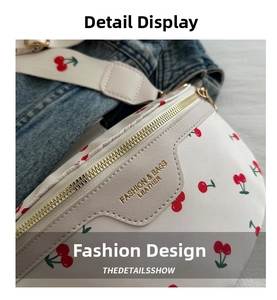 Detail of white waist bag with red cherry prints, gold zippers and fashion engraving